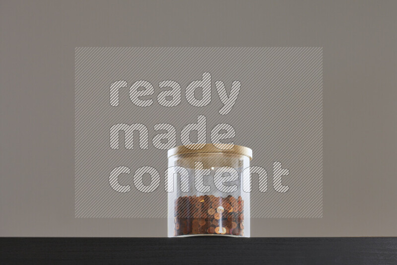 Sequins in a glass jar on black background