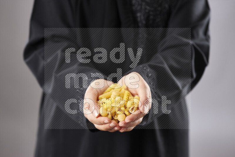 Woman in abaya holding different kinds of pasta in different positions