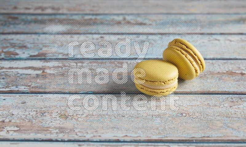 45º Shot of two Yellow Lime macarons on light blue wooden background