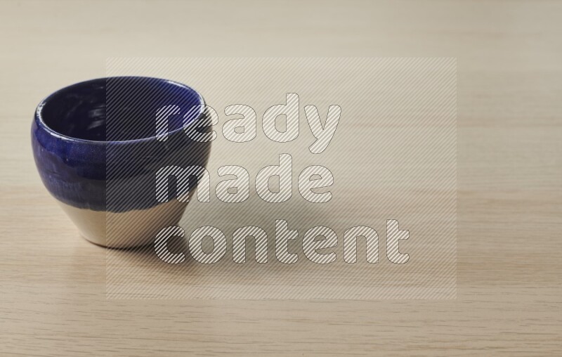 A multicolored pottery bowl on light wooden background