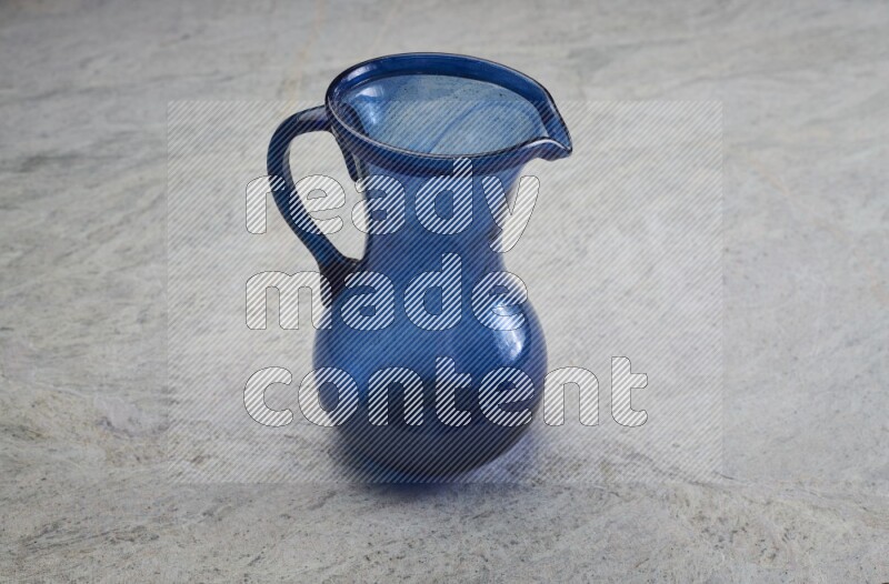 A colored glass jug on grey marble background