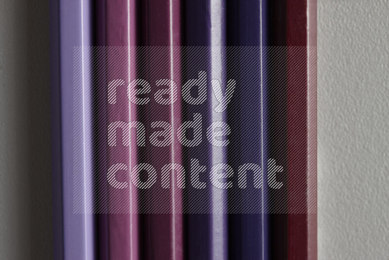 مجموعة من أقلام الرصاص الملونة مرتبة لتعرض تدرجا من الألوان الأرجوانية علي خلفية رمادية