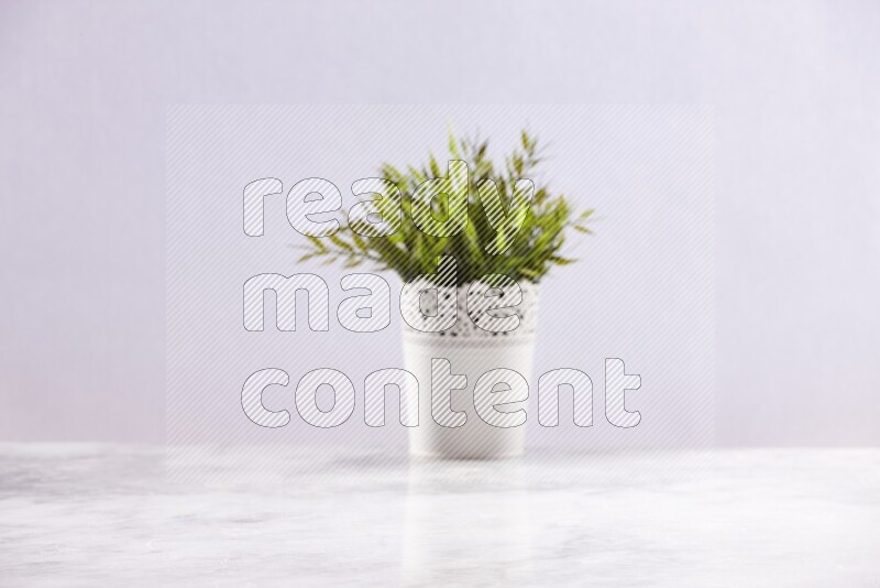 Artificial plant in white decorative pot on grey marble background