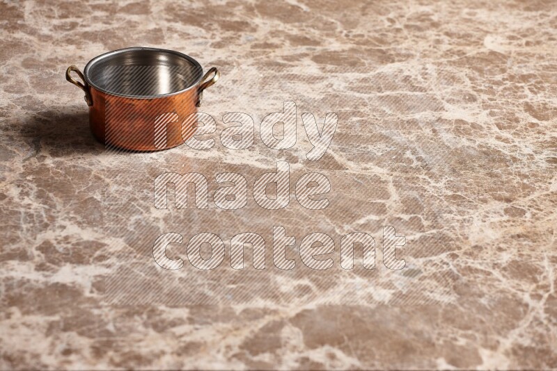 A small copper pot on beige marble background