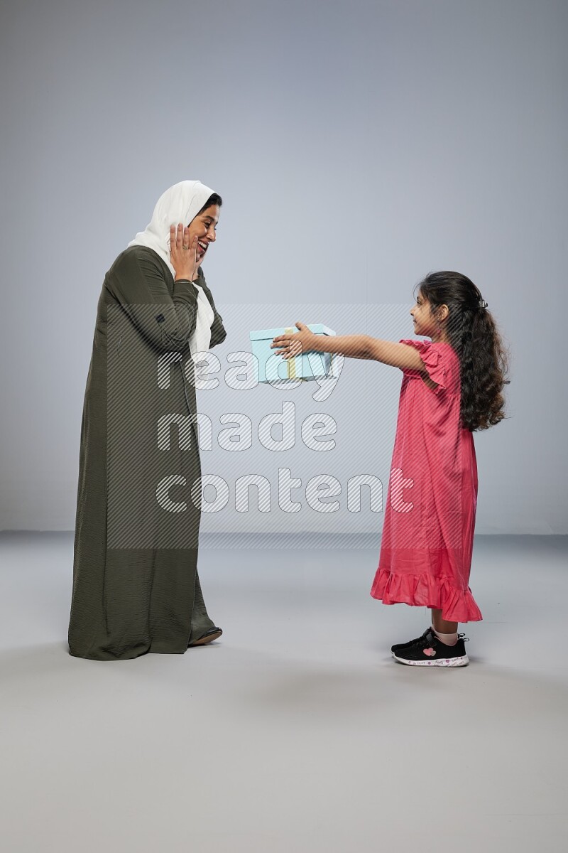 A girl giving a gift to her mother on gray background