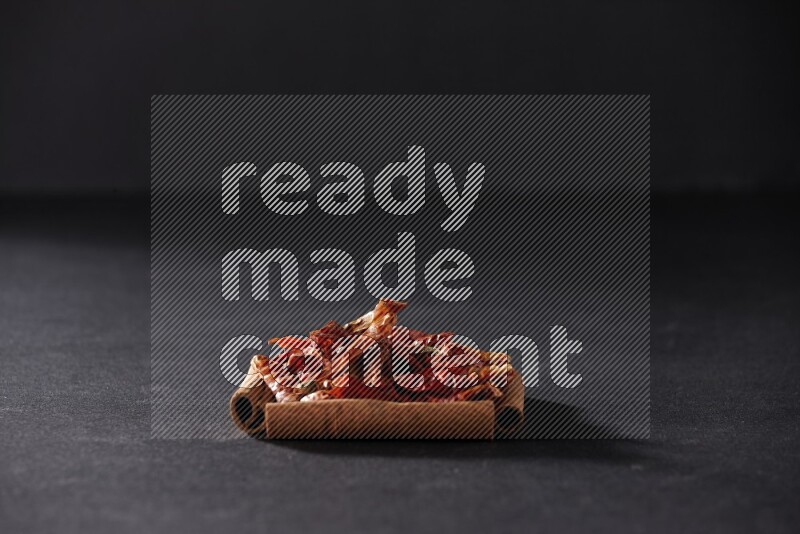 A single square of cinnamon sticks full of chilis on black flooring