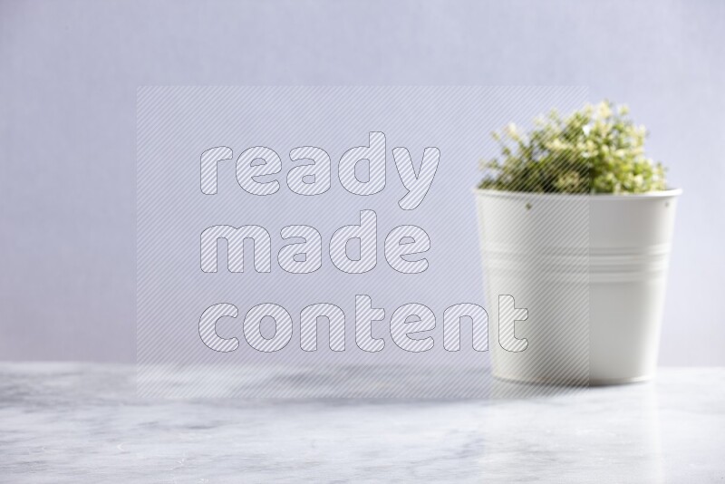 Artificial plant in white pot on grey marble background
