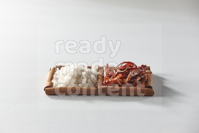 مربعان من أعواد القرفة ممتلئان بالفلفل الحار المجفف والملح الأبيض علي خلفية بيضاء