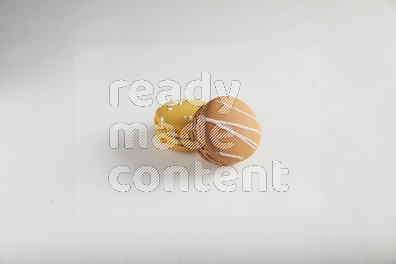 45º Shot of of two assorted Brown Irish Cream, and Yellow Piña Colada macarons on white background