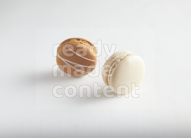 45º Shot of of two assorted Brown Irish Cream, and White Caramel fleur de sel macarons on white background