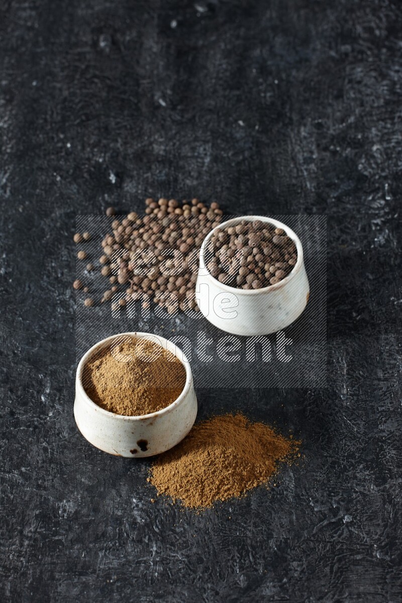 وعاءان بيج، أحدهما ممتلئ ببودرة بهار الفلفل الحلو والآخر بالحبوب وكلاهما متناثران على خلفية سوداء