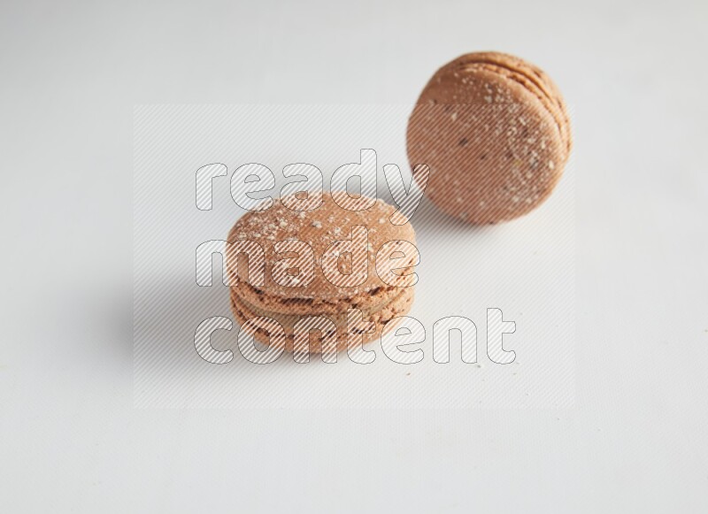 45º Shot of two Brown Hazelnuts macarons on white background