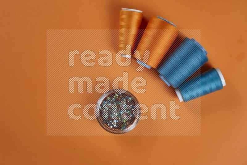 A blue collection of sewing and tailoring tools arranged on a orange background