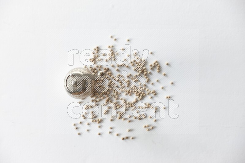 White pepper beads with a metal grinder on white flooring