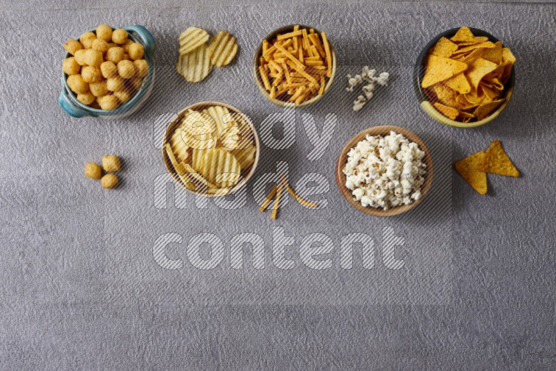 Assorted snacks in pottery bowls on grey background