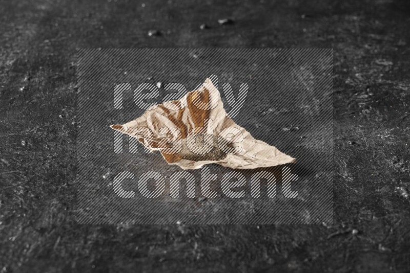 بودرة الفلفل الأسود في قطعة من الورق علي خلفية سوداء