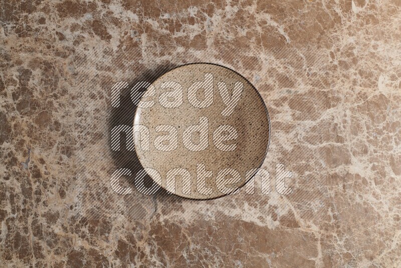 A beige pottery plate on beige marble background