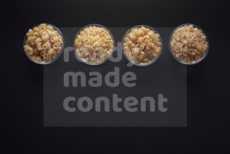 أنواع مختلفة من المعكرونة في وعاء زجاجي علي خلفية سوداء