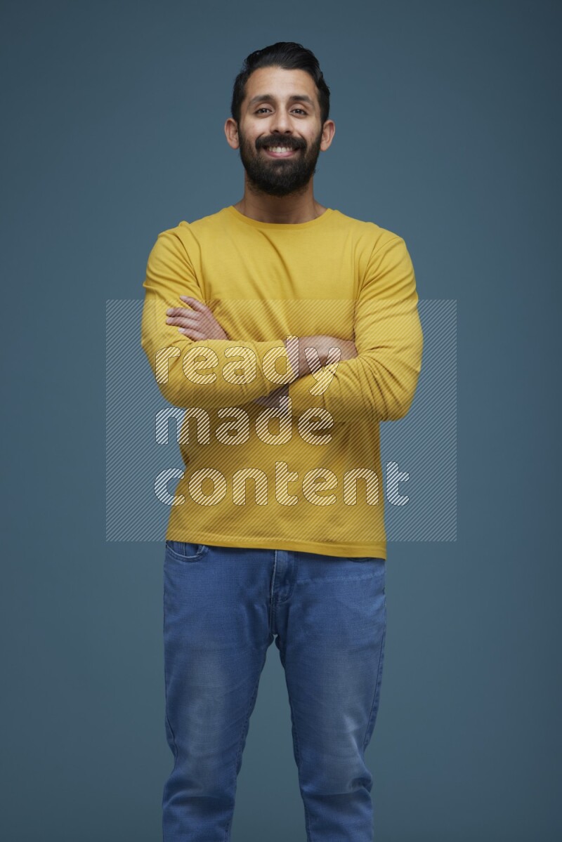 Man posing in a blue background wearing a yellow shirt