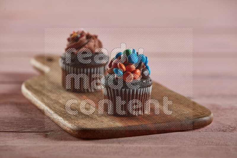 Chocolate mini cupcake topped with m&ms on a wooden board