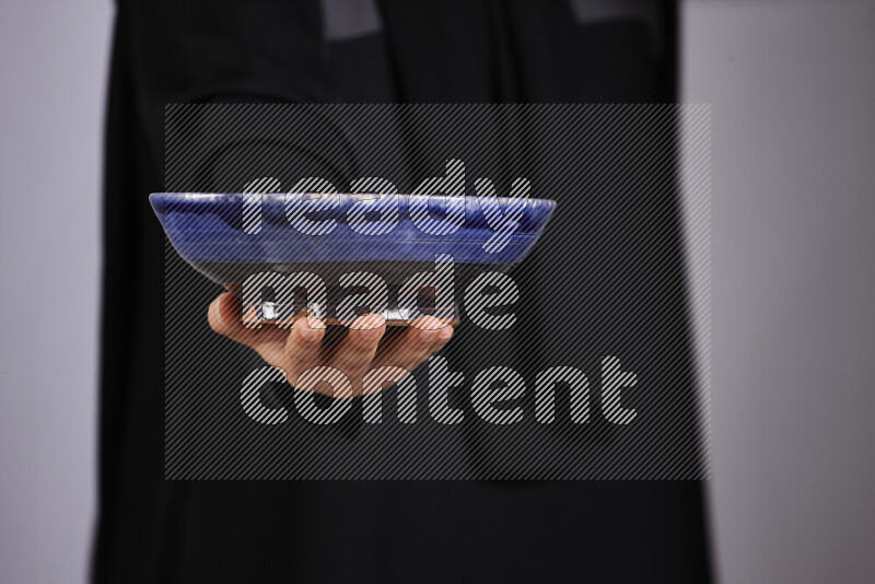 A woman in black abaya holding different pottery essentials in different positions