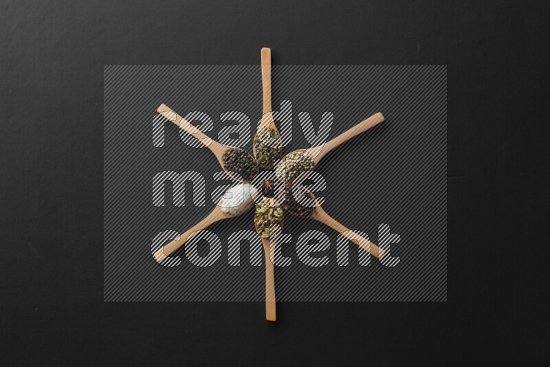 الفلفل الأبيض والقرنفل والهيل والملح والفلفل الأسود والريحان المجفف في معالق خشبية علي شكل ساعة علي خلفية سوداء