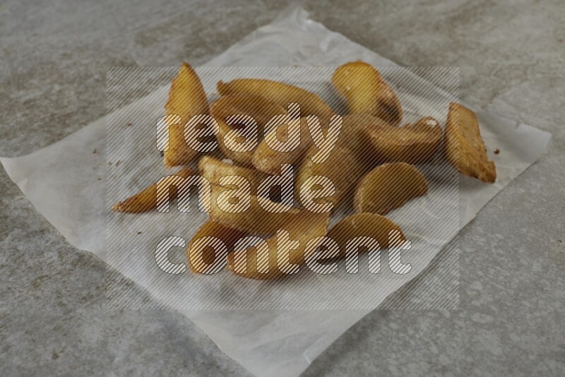 wedges potato on parchment paper on grey textured counter top