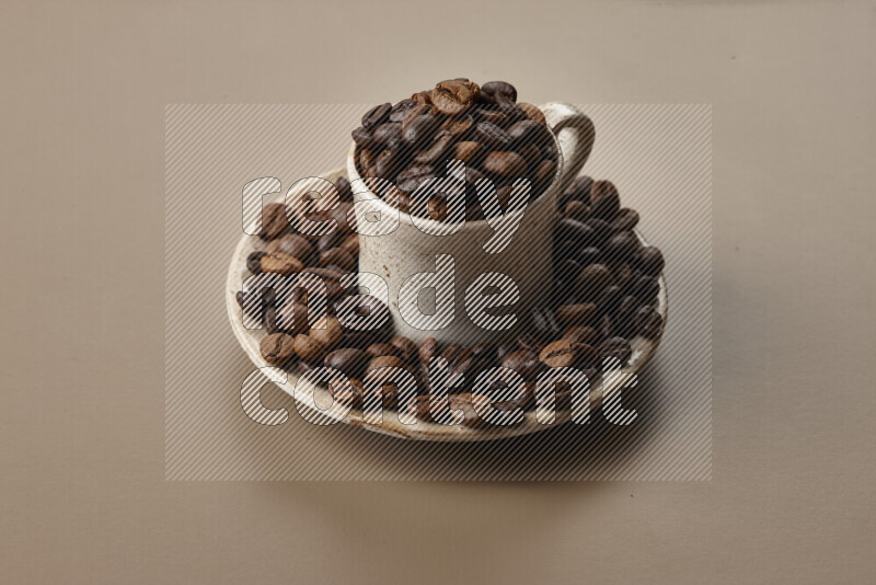 A beige pottery cup full of roasted coffee beans on beige background