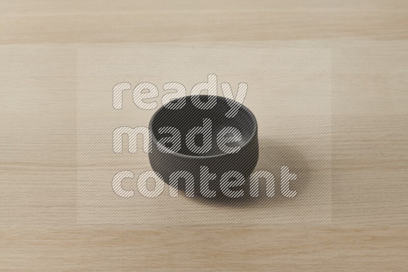 A black pottery bowl on light wooden background