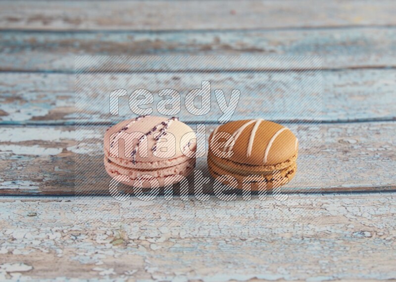 45º Shot of of two assorted Brown Irish Cream, and pink orange blossom  macarons on light blue background