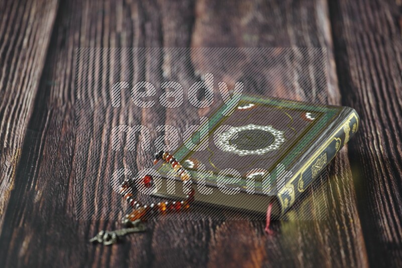 Quran with dates, prayer beads and different drinks all placed on wooden background
