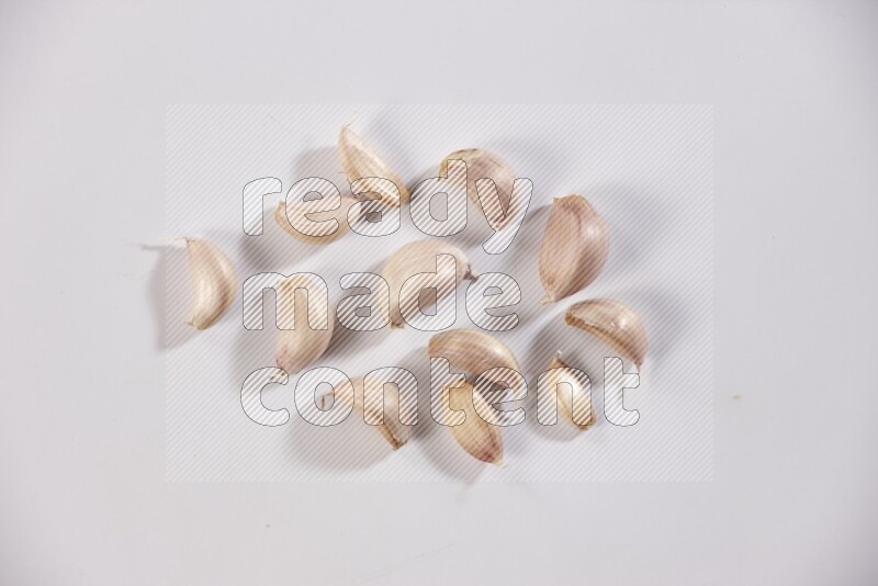 Scattered garlic cloves on a white flooring