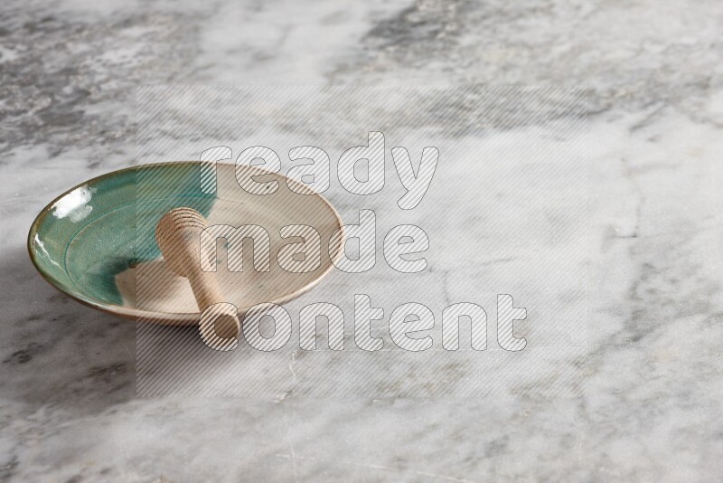 Multicolored pottery plate with wooden honey dipper in it on grey marble background