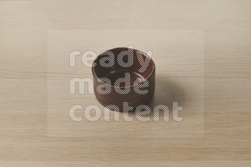 A brown pottery bowl on light wooden background
