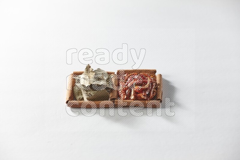 2 squares of cinnamon sticks full of dried red chilis and bay laurel leaves on white flooring