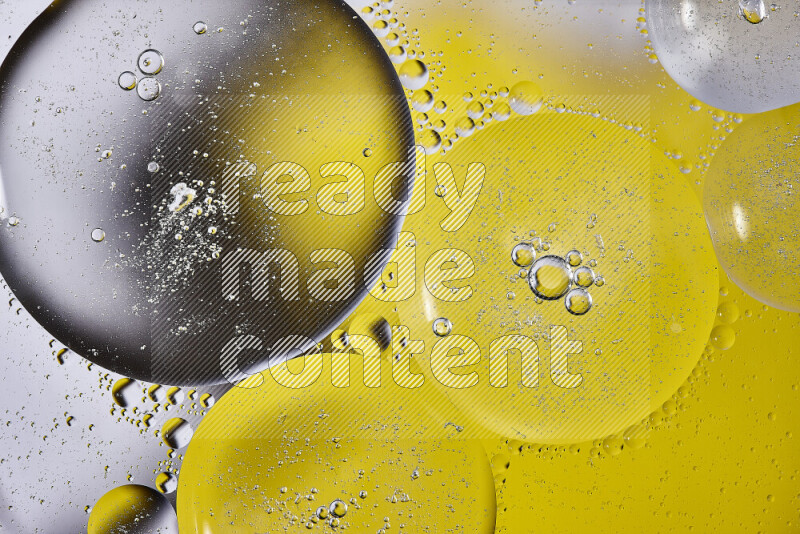 Close-ups of abstract oil bubbles on water surface in shades of black and yellow