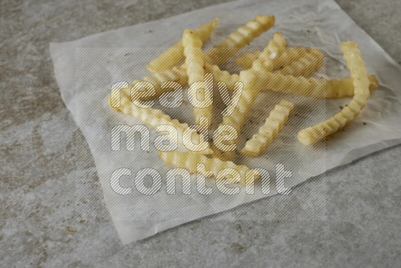 crinkle fries on parchment paper on grey textured counter top
