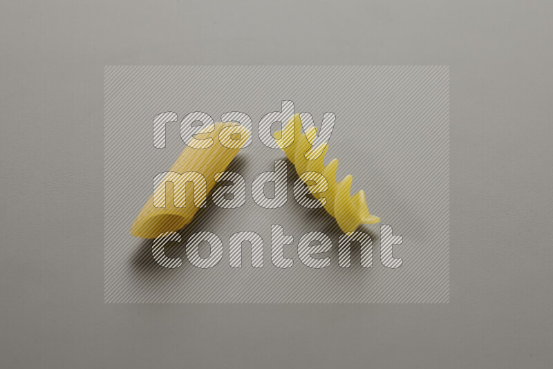 Penne pasta with other types of pasta on grey background