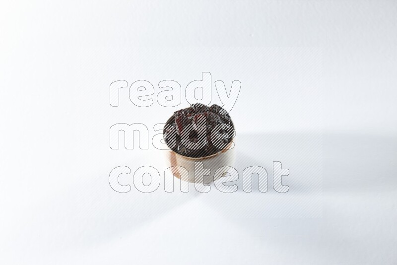A beige ceramic bowl full of dried plums on a white background in different angles