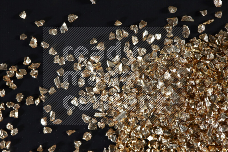 Gold shimmering fragments of glass scattered on a black background