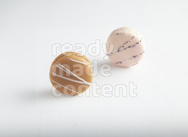 45º Shot of of two assorted Brown Irish Cream, and pink orange blossom macarons on white background