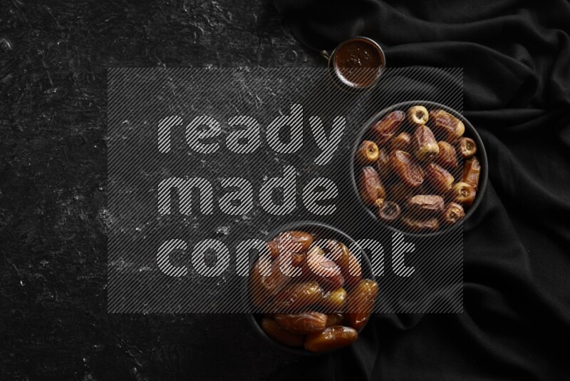 Dates in pottery bowls with coffee in a dark setup