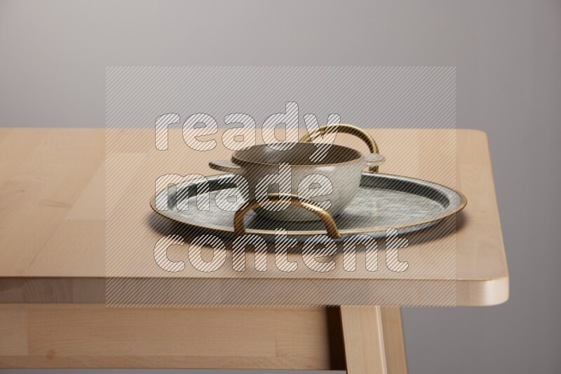 off white bowl placed on a rounded stainless steel tray with golden handels on the edge of wooden table