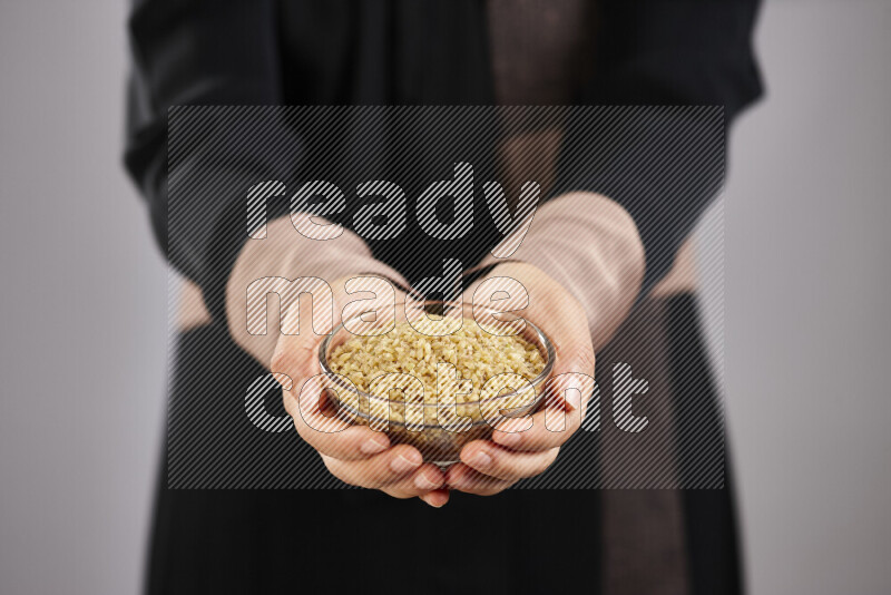 Woman in abaya holding different kinds of legumes in different positions