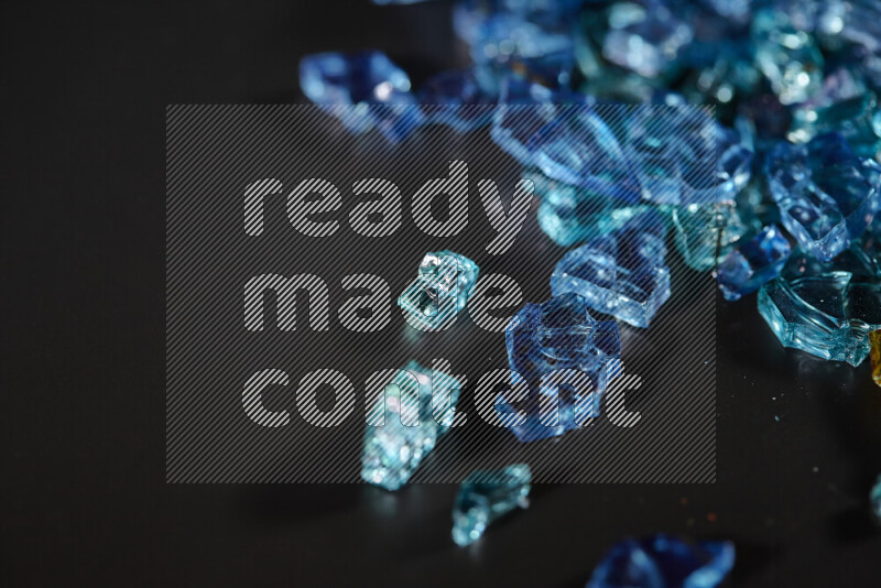 Transparent blue fragments of glass scattered on a black background