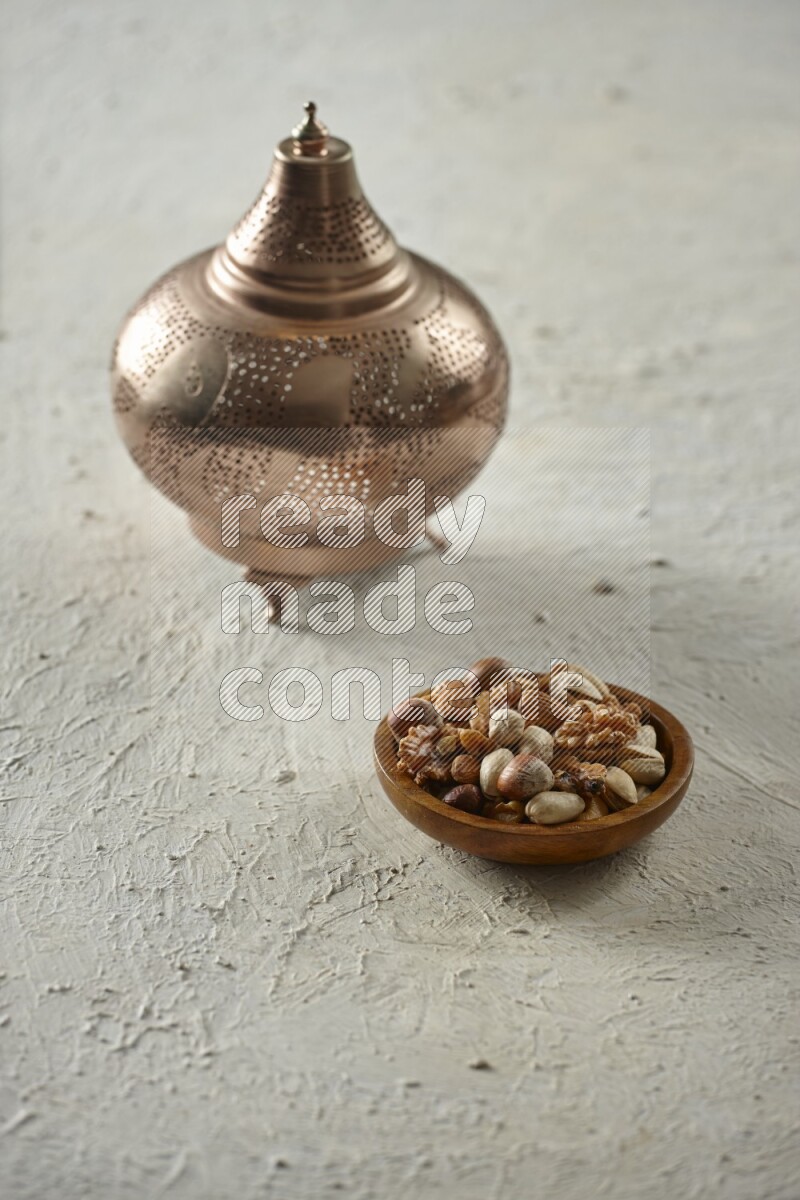 A golden lantern with different drinks, dates, nuts, prayer beads and quran on textured white background