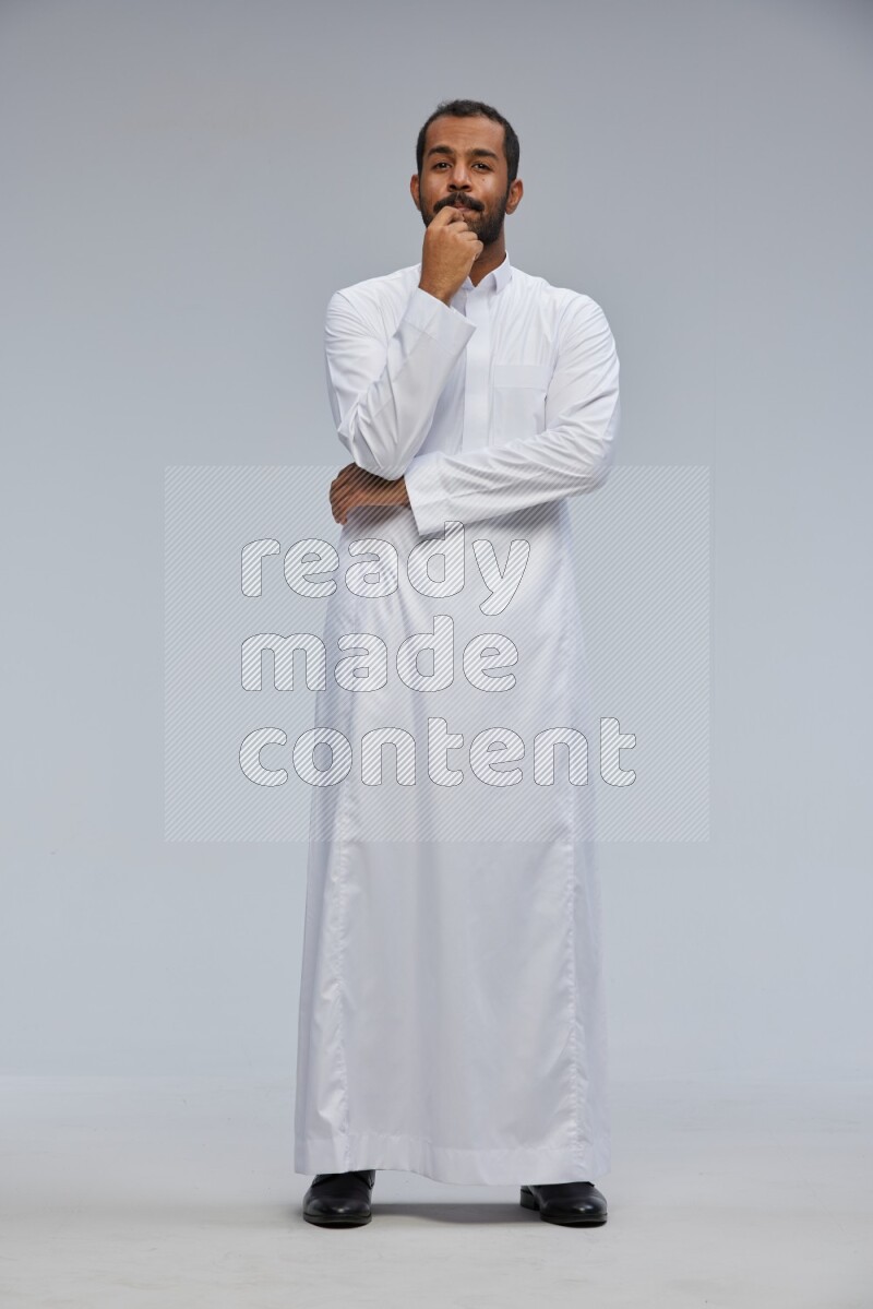 Saudi man Wearing Thob standing interacting with the camera on Gray background