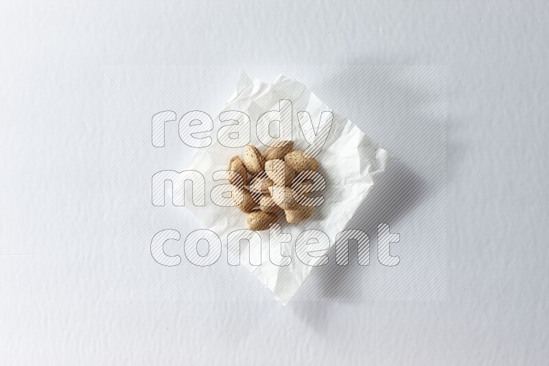 Almonds on a crumpled piece of paper on a white background in different angles