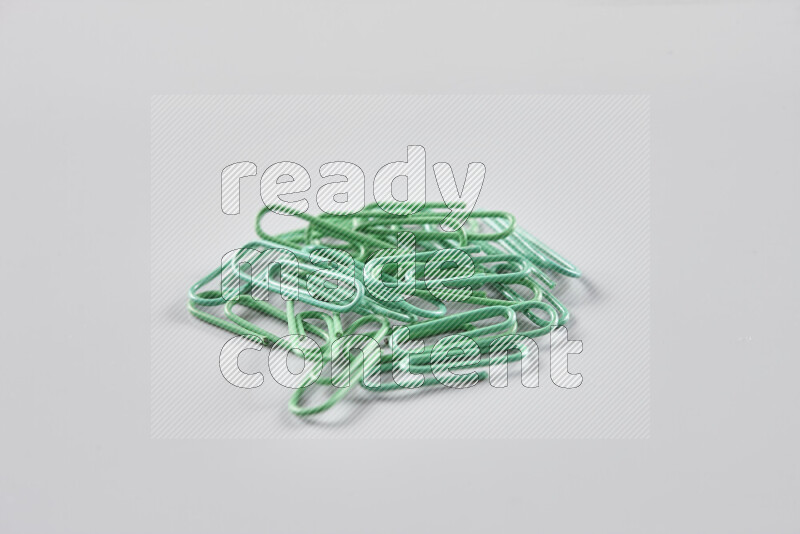 Green paper clips isolated on a grey background