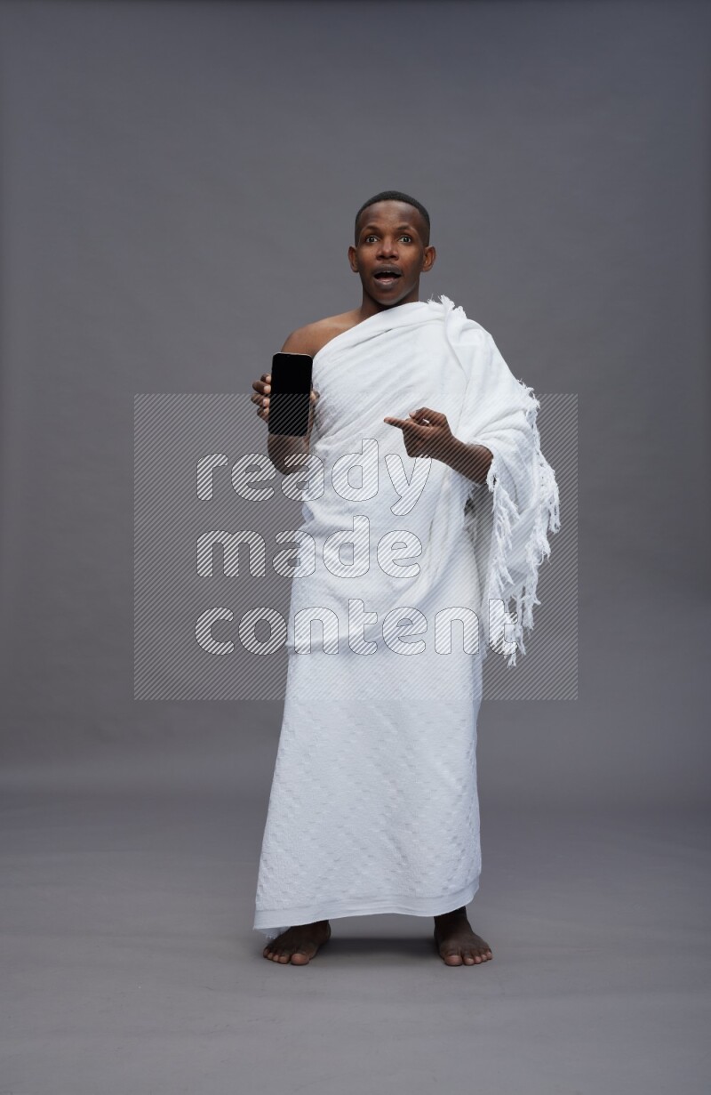 A man wearing Ehram Standing showing phone to camera on gray background